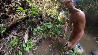 A couple has fun on the riverbank surrounded by jungle vegetation