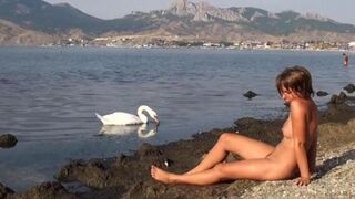 A hot chick is walking naked on the riverbank and showing her body