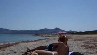 Blonde woman makes a blowjob to her lover on the beach