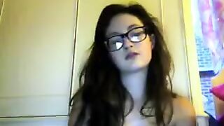 A cute girl in glasses takes her clothes off on the webcam