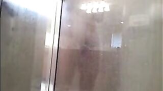 A man washes his body in the shower, unaware of being filmed