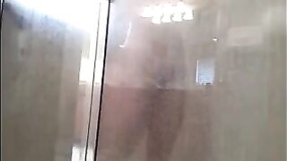 A man washes his body in the shower, unaware of being filmed
