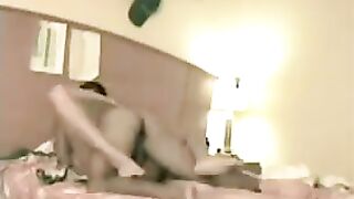 A couple has sex on the bed, captured in a hidden camera shot