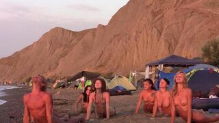 A group of naked people playing volleyball on the beach