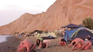 A group of naked people playing volleyball on the beach